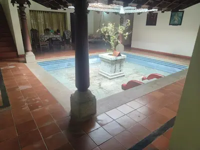 a pool with a table and chairs and a pole at Utthara Tharavadu in Irinjālakuda