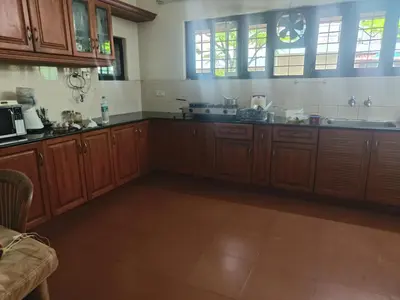 a large kitchen with wooden cabinets and windows at Utthara Tharavadu in Irinjālakuda