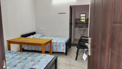 a small room with two beds and a table at Voyagers Nest Wayanad in Ambalavayal