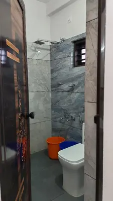 a bathroom with a toilet and a wall with a stone wall at Voyagers Nest Wayanad in Ambalavayal