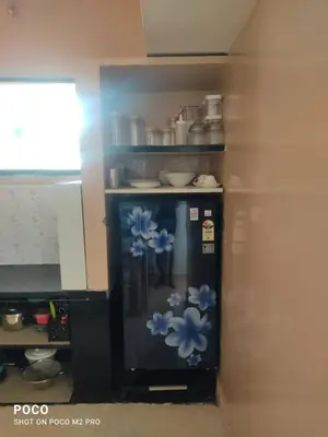 a microwave with blue flowers painted on it in a kitchen at Sumukh's house in Mysore