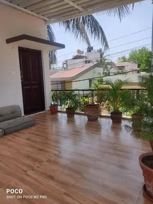 a large room with a wooden floor and potted plants at Sumukh's house in Mysore