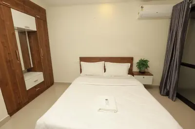 a bedroom with a large white bed with a wooden headboard at LAVENDER AiRPORT SUiTE in Nedumbassery
