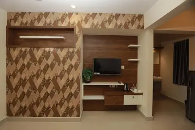 a room with a wall with a tv and a desk at LAVENDER AiRPORT SUiTE in Nedumbassery
