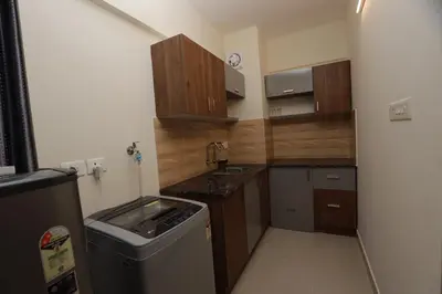 a small kitchen with wooden cabinets and a sink at LAVENDER AiRPORT SUiTE in Nedumbassery