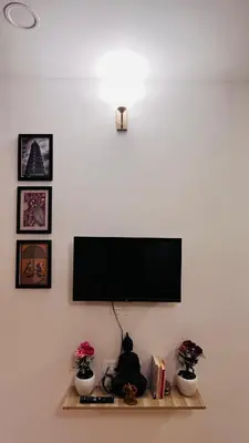 a flat screen tv on a wall with a shelf at SKYRIN Bliss in Mysore