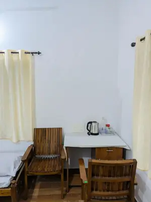 a room with a table and two chairs and a table with a kettle at Gods Gift Homestay James Inn in Kozhikode