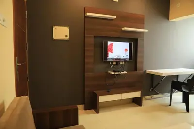 a room with a tv on a wall with a desk at Ambalath whitespring in Guruvāyūr