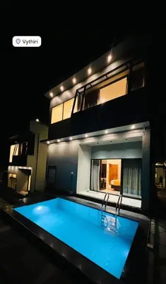 a swimming pool in front of a house at night at LA VILLA Resort in Vythiri