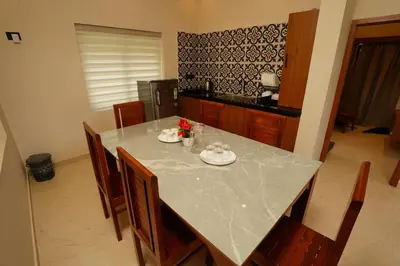 a kitchen with a table with chairs and a white counter top at LA VILLA Resort in Vythiri