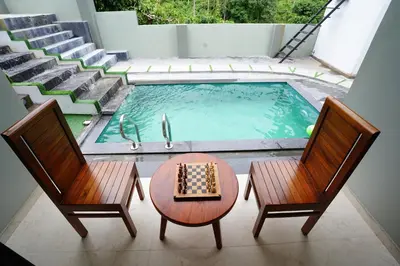 a pool with two chairs and a chessboard on a table next to a table at LA VILLA Resort in Vythiri