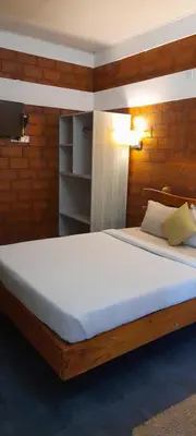 a bedroom with a large bed with white sheets at Atithi Devo Resort Coorg by LexStays in Kushālnagar