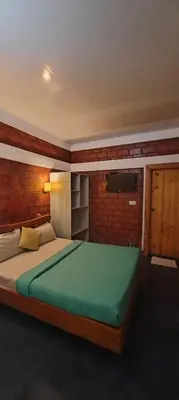 a bedroom with a large bed and a television at Atithi Devo Resort Coorg by LexStays in Kushālnagar