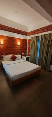 a bedroom with a large bed and a brick wall at Atithi Devo Resort Coorg by LexStays in Kushālnagar