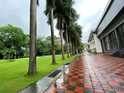 a wet sidewalk with palm trees next to a building at Hotel KPM Tripenta in Palakkad