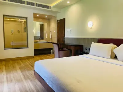 a bedroom with a large bed and a bathroom at Hotel KPM Tripenta in Palakkad