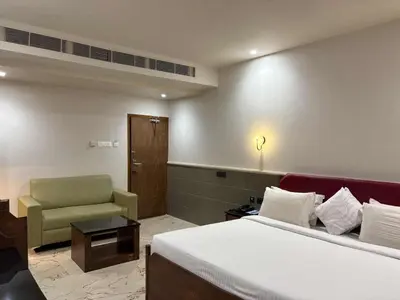 a hotel room with a bed and a chair at Hotel KPM Tripenta in Palakkad