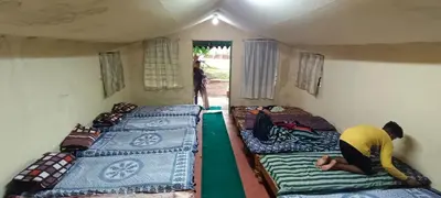 a man in a small room with three beds at Lucky Escape Adda in Hullahalli