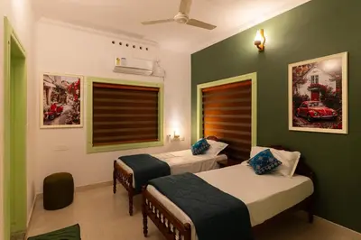 two beds in a room with green walls at GEE DE Homes in Kizhake Chālakudi