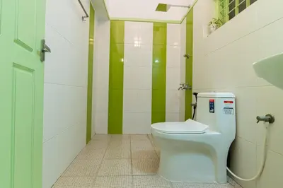 a bathroom with a toilet and a green and white wall at GEE DE Homes in Kizhake Chālakudi