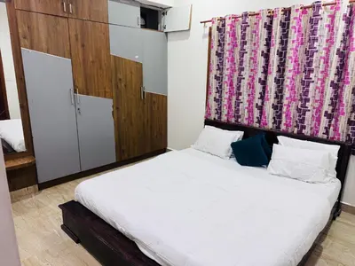 a bedroom with a white bed with a pink curtain at LUXE Premium Service Appartment in Mysore