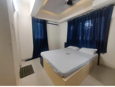 a small bed in a room with blue curtains at Ambadi Blueberry in Guruvāyūr