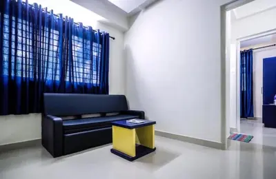 a living room with a black couch and a yellow stool at Ambadi Blueberry in Guruvāyūr