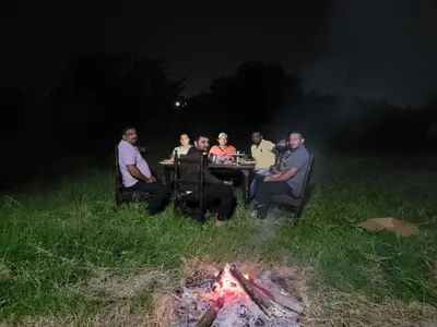 a group of people sitting around a table around a fire at Mountain View Stay in Kushālnagar