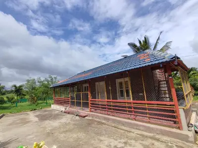 a small building with a roof with a palm tree at Mountain View Stay in Kushālnagar