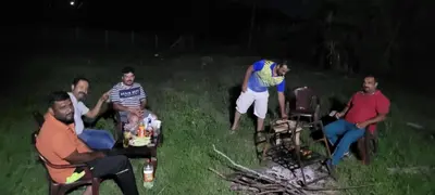 a group of people sitting around a campfire at night at Mountain View Stay in Kushālnagar