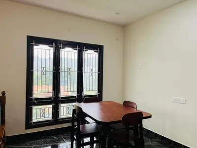 a dining room with a wooden table and two windows at Away From Home - 8 - HomeStay, Entire 2 BHK Villa in Ooty