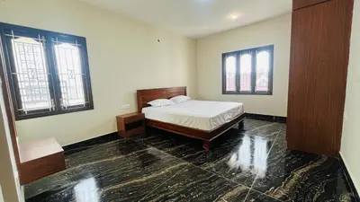a bedroom with a bed and two windows at Away From Home - 8 - HomeStay, Entire 2 BHK Villa in Ooty