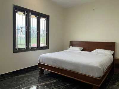 a bedroom with a bed and two windows at Away From Home - 9 - HomeStay, Entire 2 BHK Villa in Ooty