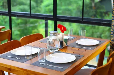 a wooden table with plates and a vase with a flower on it at Swiss Holidays in Pinangode