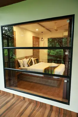 a bedroom with a bed inside of a glass window at Swiss Holidays in Pinangode