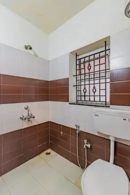 a bathroom with a toilet and a window at A Ooty Garden Residency in Ooty