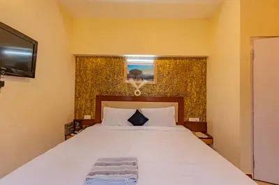 a bedroom with a large white bed and a television at A Ooty Garden Residency in Ooty
