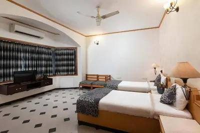 a hotel room with two beds and a flat screen tv at Dwaraka inn -Premium Pool villa and event venue in Coimbatore
