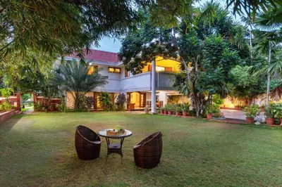 a house with two chairs and a table in the yard at Dwaraka inn -Premium Pool villa and event venue in Coimbatore
