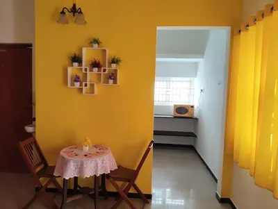 a dining room with a table and a yellow wall at A Cozy Homestay in Coimbatore in Coimbatore