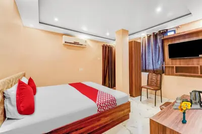 a bedroom with a bed with red pillows and a tv at Hotel O Sulur Bus Terminal Formerly Sri Sakthi Vinayagar Residency
