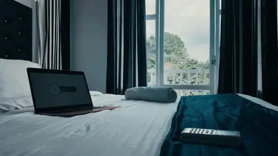 a laptop computer sitting on a bed with a remote control at Aura 2Bedroom Duplex Villa with infinity pool in Kalpetta