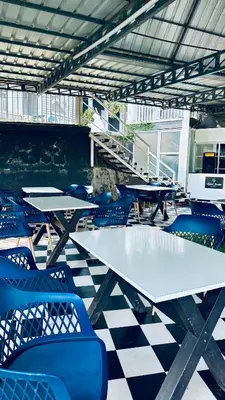 a group of tables and blue chairs in a room at Aura 2Bedroom Duplex Villa with infinity pool in Kalpetta