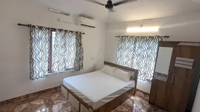 a small room with a bed and two windows at Lush Lagoon Homestay in Ambalavayal