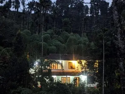a house with its lights on in the forest at night at Lush Lagoon Homestay in Ambalavayal