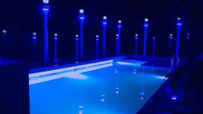 a swimming pool with blue lights in the dark at AppleLand City Athirapilly by Hotels Cart in Athirappally