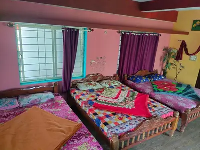 two beds in a room with purple curtains at Laali Dormitory in Madikeri