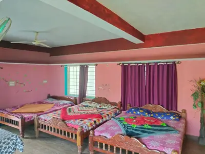 two beds in a room with pink walls at Laali Dormitory in Madikeri