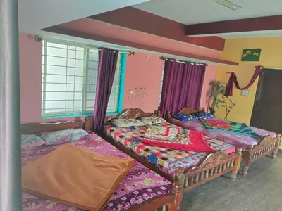 two beds in a room with purple walls at Laali Dormitory in Madikeri