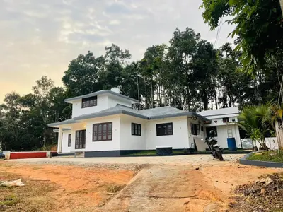 a white house with a motorcycle parked in front of it at The Soul 1 Service Villa in Mananthavady